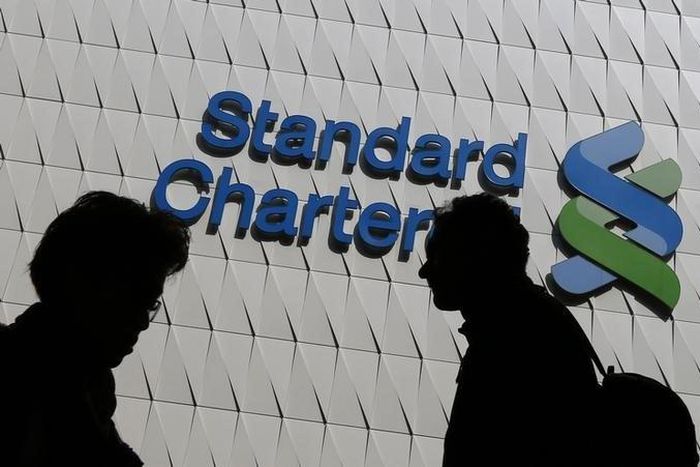 Passersby walk in front of the main branch of Standard Chartered in Hong Kong, in this January 8, 2015 file photo. REUTERS/Bobby Yip