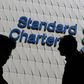 Passersby walk in front of the main branch of Standard Chartered in Hong Kong, in this January 8, 2015 file photo. REUTERS/Bobby Yip