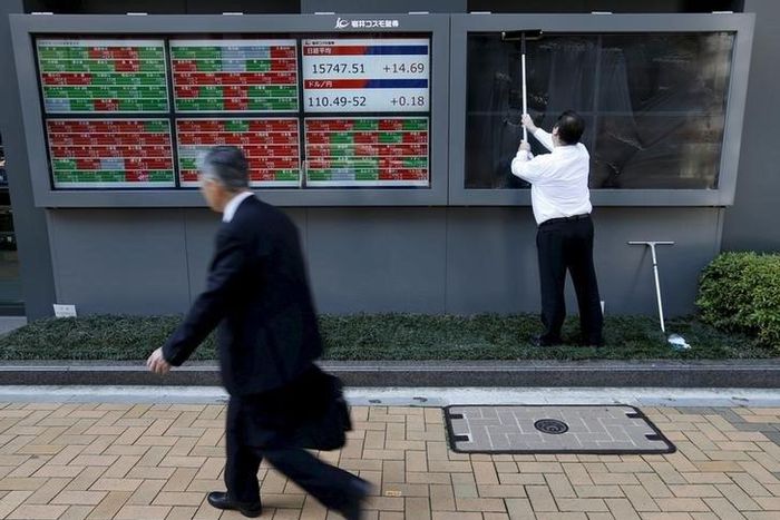 A man (R) cleans electronic boards showing Japan's Nikkei average, the exchange rate between the Japanese yen against the U.S. dollar and stock quotation outside a brokerage in Tokyo, Japan, in this April 6, 2016 file photo. REUTERS/Issei Kato/Files