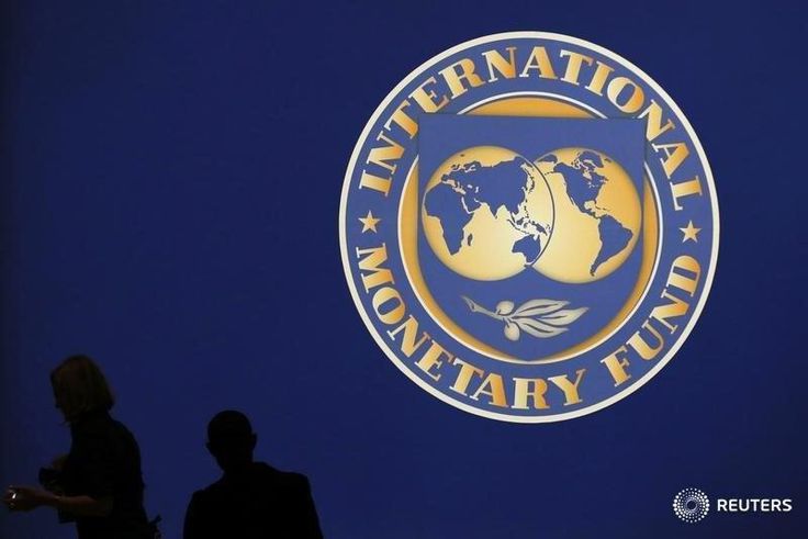 Visitors are silhouetted against the logo of the International Monetary Fund at the main venue for the IMF and World Bank annual meeting in Tokyo October 10, 2012.
