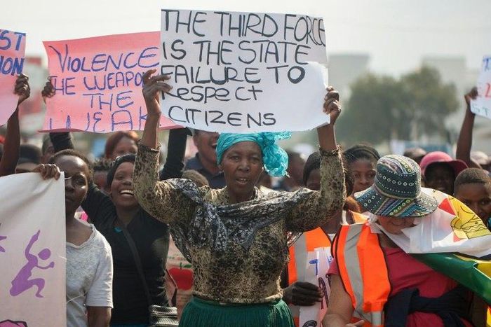 People sing political slogans and hold placards as they march through the streets of Bulawayo during a protest against police brutality, corruption and state of the economy on July 26, 2016 in Bulawayo 