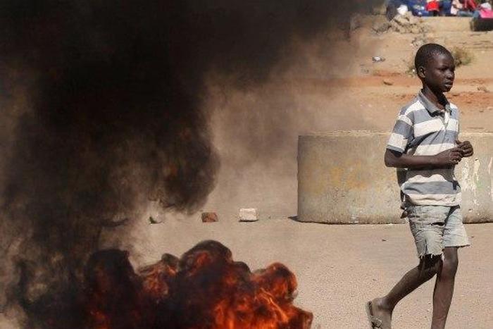 A boy walks past a burning tyre in Mufakose in Harare, Zimbabwe, July 6, 2016. REUTERS/Philimon Bulawayo