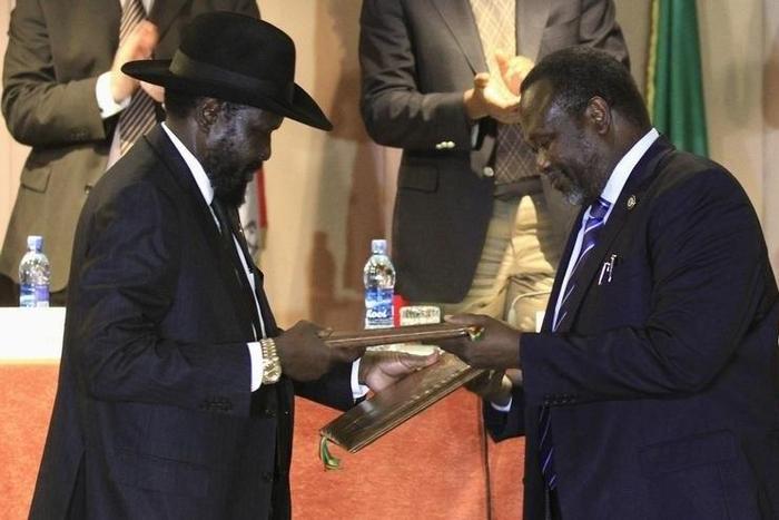 South Sudan's President Salva Kiir (L) and South Sudan's rebel commander Riek Machar exchange documents after signing a ceasefire agreement during the Inter Governmental Authority on Development (IGAD) Summit on the case of South Sudan in Ethiopia's ca...