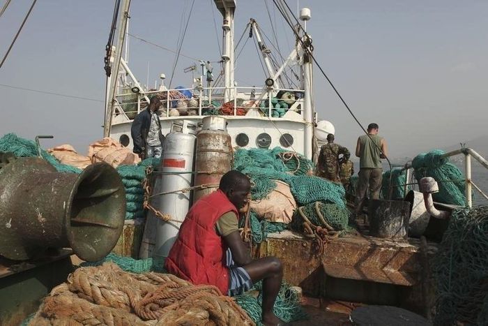 A crew member sits on a fishing net as Sierra Leonean security forces guard the Marampa 803, a vessel apprehended for alleged illegal fishing activities, that has been moored off the West African country's capital Freetown January 21, 2012.