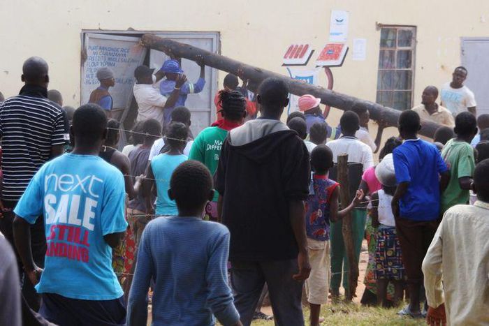 People use a pole to batter a shop doorway during clashes with police in Lusaka April 19, 2016.