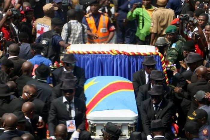 A general view taken through a window shows mourners escorting the casket of legendary Congolese singer Papa Wemba, born Jules Shungu Wembadio Pene Kikumba, from the the Notre Dame du Congo Cathedral for burial, along the streets of the Democratic Repu...