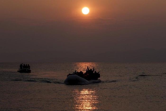 Refugees and migrants wave as they approach the shores of the Greek island of Lesbos on a dinghy during sunrise, March 20, 2016. REUTERS/Alkis Konstantinidis