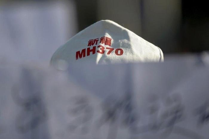 A family member of a passenger onboard Malaysia Airlines flight MH370 which went missing in 2014 holds a banner during a gathering in front of the Malaysian Embassy on the second anniversary of the disappearance of MH370, in Beijing, China, March 8, 20...