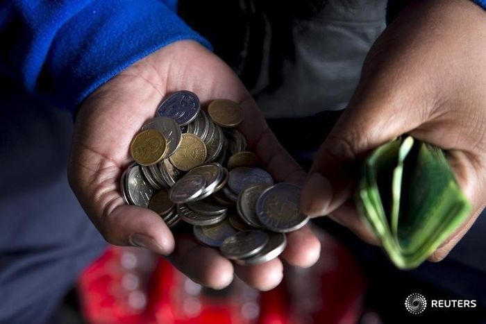 A street trader counts out change for a customer in Durban, September 8, 2015.