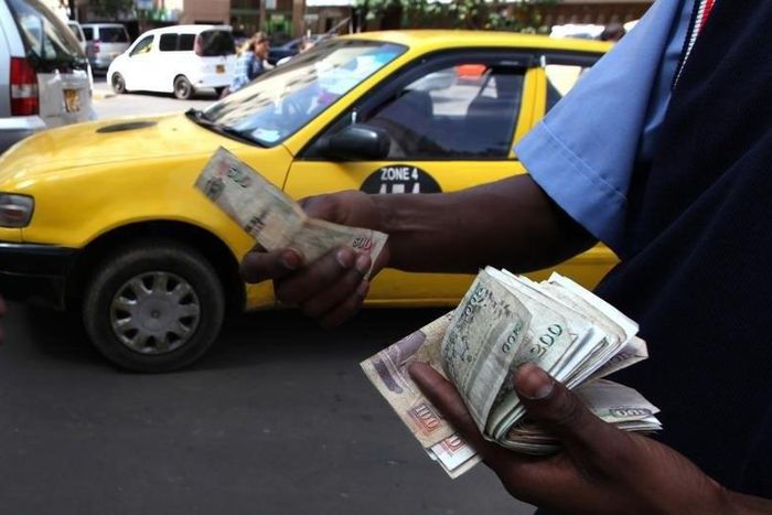 A fuel attendant handles Kenyan shilling notes at a petrol station in the capital Nairobi March 15, 2011.   REUTERS/Noor Khamis