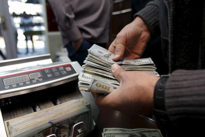 A man counts wads of U.S. dollars on a money counting machine at a currency exchange shop in Baghdad December 21, 2015. REUTERS/Khalid al Mousily