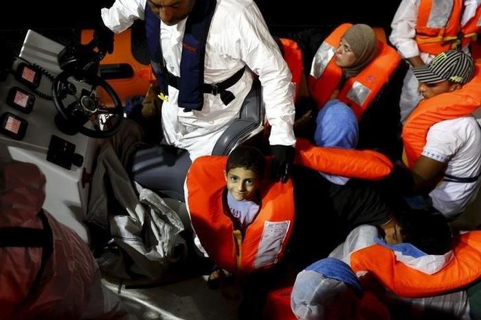 A migrant child smiles as he waits to be transferred from the Migrant Offshore Aid Station (MOAS) ship MV Phoenix to the Norwegian ship Siem Pilot off the coast of Libya August 6, 2015.