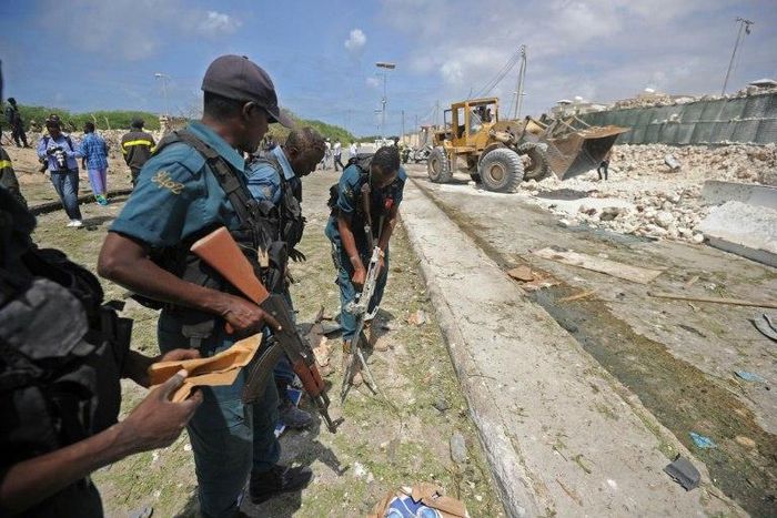 Somali soldiers secure a partially-crumbled perimeter wall following twin car bombings outside UN buildings in Mogadishu on July 26