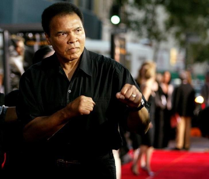 Boxing legend Muhammad Ali (R) jabs at photographers while arriving at the Orpheum Theatre for the premiere of the film "Collateral" in Los Angeles in this August 2, 2004 file photo. REUTERS/Robert Galbraith/File Photo
