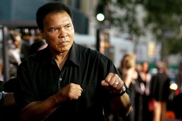 Boxing legend Muhammad Ali (R) jabs at photographers while arriving at the Orpheum Theatre for the premiere of the film "Collateral" in Los Angeles in this August 2, 2004 file photo. REUTERS/Robert Galbraith/File Photo