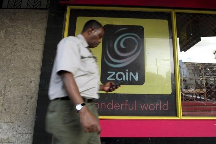 A man uses his mobile phone as he walks past a Zain customer care shop in Nairobi February 15, 2010.  REUTERS/Thomas Mukoya