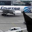 A passenger reads a newspaper at a departure hall of London's Heathrow terminal as an EgyptAir plane taxis on the tarmac of the airport May 20, 2016.