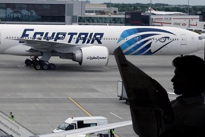 A passenger reads a newspaper at a departure hall of London's Heathrow terminal as an EgyptAir plane taxis on the tarmac of the airport May 20, 2016.