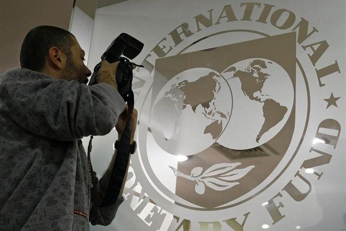A photographer takes pictures through a glass carrying the International Monetary Fund (IMF) logo during a news conference in Bucharest in a file photo.