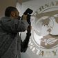 A photographer takes pictures through a glass carrying the International Monetary Fund (IMF) logo during a news conference in Bucharest, file.