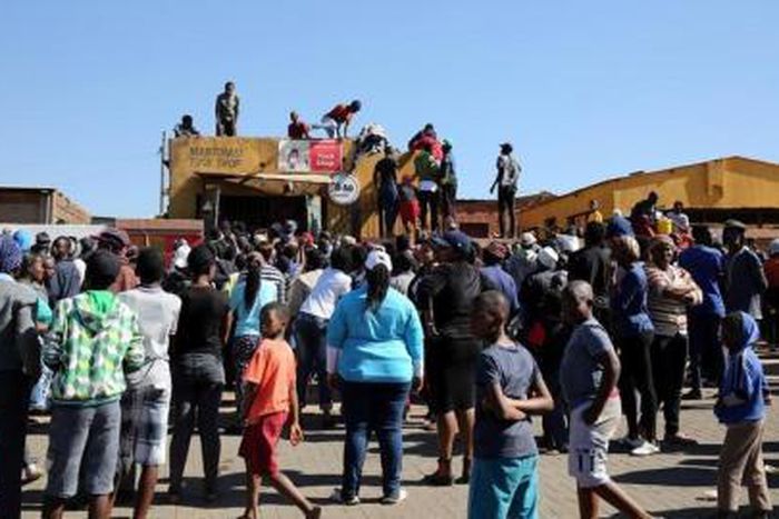 Locals attempt to gain access to a shop before looting during protests in Atteridgeville, a township located to the west of Pretoria, South Africa June 21, 2016.