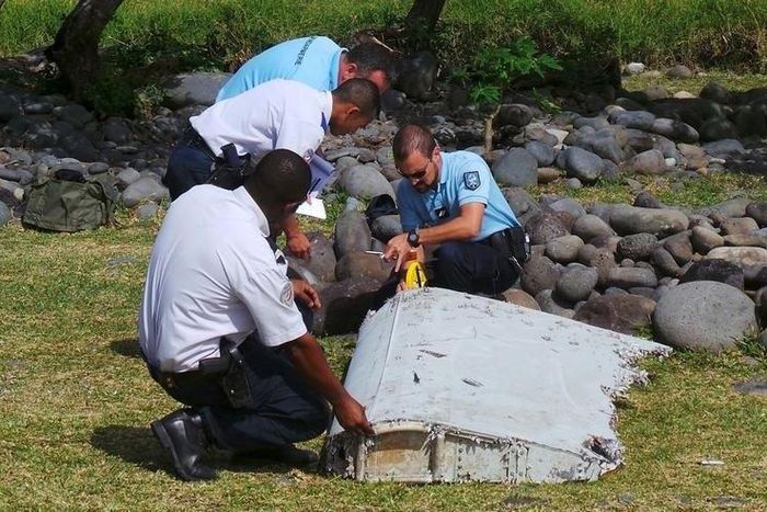 File picture shows French gendarmes and police inspecting a large piece of plane debris which was found on the beach in Saint-Andre, on the French Indian Ocean island of La Reunion, July 29, 2015.