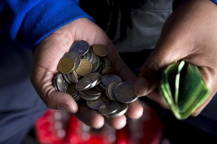 A street trader counts out change for a customer in Durban, September 8, 2015.