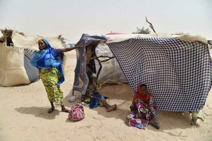 This photo taken on June 19, 2016 in the village of Kidjendi near Diffa shows women standing near makeshift tent in a camp as displaced families fled from Boko Haram attacks in Bosso