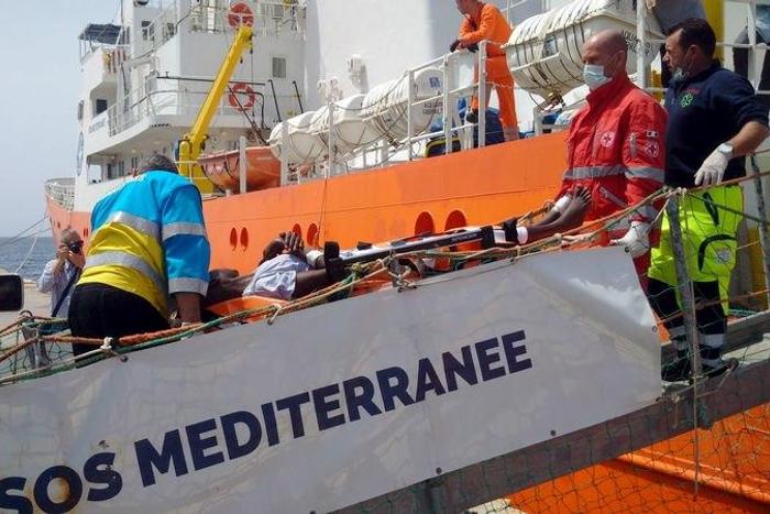 A migrant receives help when disembarking from the SOS Mediterranee ship Aquarius at the Italian island of Lampedusa in this handout received April 18, 2016.