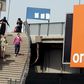 People walk past a sign of French telecom operator Orange hanging from a bridge in Cairo, Egypt March 13, 2016.