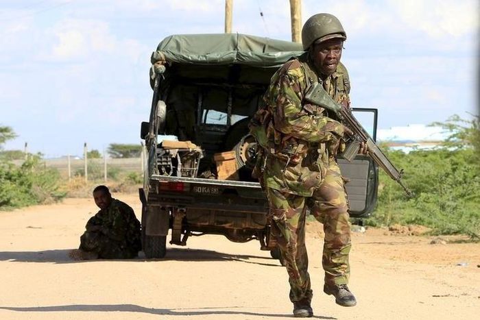 A Kenya Defense Force soldier runs for cover near the perimeter wall where attackers are holding up at a campus in Garissa April 2, 2015. A REUTERS/Noor Khamis