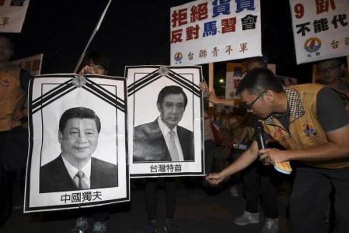 A pro-Taiwan activist attempts to burn portraits of Taiwan"s President Ma Ying-jeou (R) and Chinese President Xi Jinping while protesting against the upcoming Singapore meeting between Ma and Xi, outside Taipei Songshan airport, November 7, 2015.