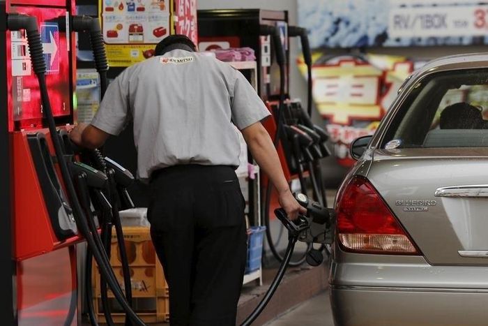 A gas station worker fuels a vehicle in Tokyo August 26, 2015. REUTERS/Toru Hanai