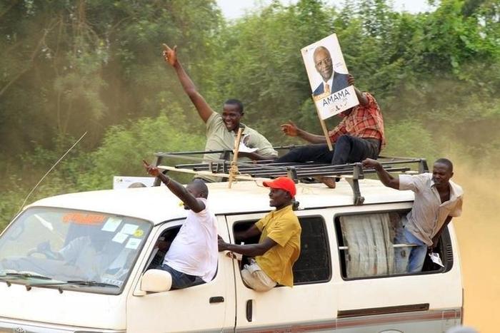 A supporter of Amama Mbabazi, former Ugandan prime minister and presidential candidate for The Democratic Alliance (TDA), holds a poster of him atop a mini bus during a campaign rally ahead of the February 18 presidential election, in Lyantonde town, U...