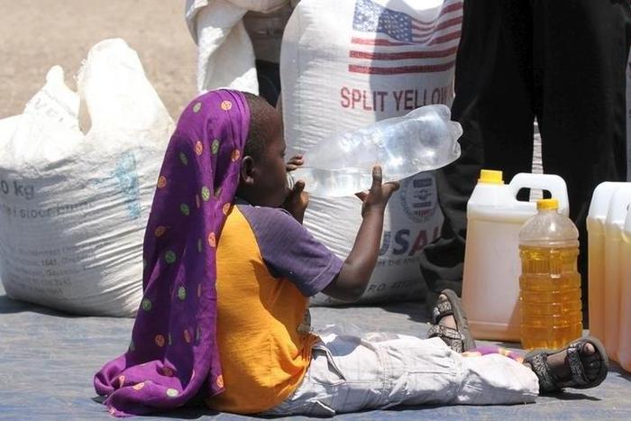 A child drinks water near the monthly food ration at a distribution center in rural Mupinga area in Chiredzi, Zimbabwe, October 6, 2015. REUTERS/Philimon Bulawayo