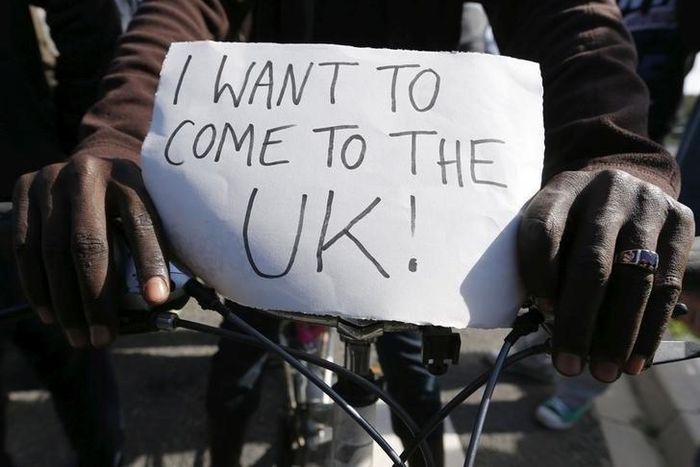A migrant holds a placard which reads "I want to come to the U.K." on his bicycle at the makeshift camp called "The New Jungle" in Calais, France, September 19, 2015. REUTERS/ Regis Duvignau