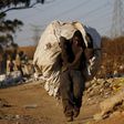 An unemployed man carries a bag full of recyclable waste material which he sells for a living, in Daveland near Soweto, South Africa August 4, 2015. REUTERS/Siphiwe Sibeko
