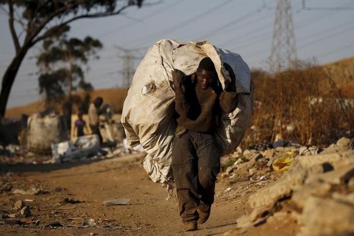 An unemployed man carries a bag full of recyclable waste material which he sells for a living, in Daveland near Soweto, South Africa August 4, 2015. REUTERS/Siphiwe Sibeko