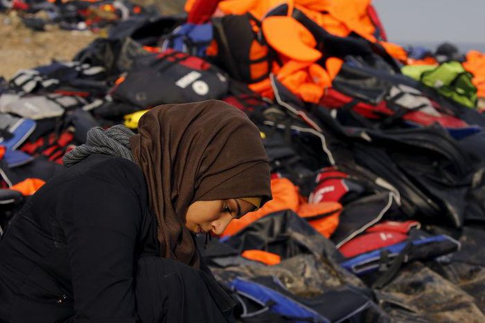 A Syrian refugee rests by a pile of life jackets after arriving in an overcrowded raft at a beach on the Greek island of Lesbos October 19, 2015. REUTERS/Yannis Behrakis
