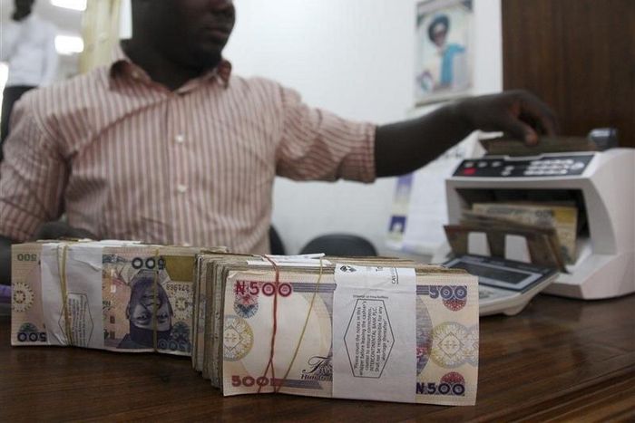 A money dealer counts the Nigerian naira on a machine in his office in the commercial capital of Lagos,   in a file photo. REUTERS/Akintunde Akinleye