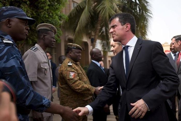 French Prime Minister Manuel Valls shakes hands with head of rapid intervention unit Commander Evrard Somda in front of Cappuccino cafe, the site of an Al Qaeda attack that killed 30 in January in Ouagadougou, Burkina Faso, February 20, 2016. REUTERS/N...