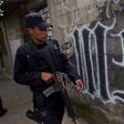 In this March 7, 2014 file photo, a member of the Salvadoran National Police walks next to graffiti of the Mara Salvatrucha gang painted on a wall.