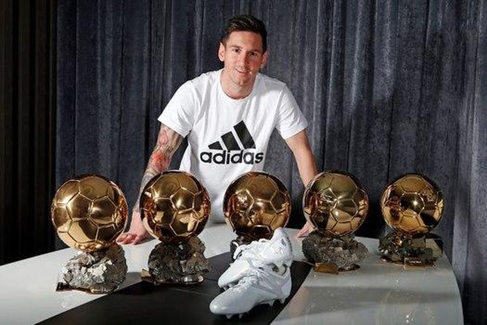 Lionel Messi poses with his five Ballon d'Or and the adidas platinum boots