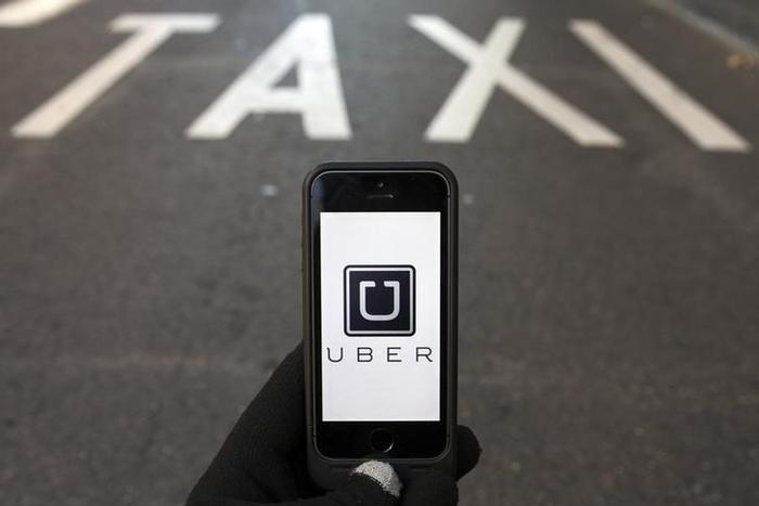 The logo of car-sharing service app Uber on a smartphone over a reserved lane for taxis in a street is seen in this photo illustration taken in Madrid on December 10, 2014. REUTERS/Sergio Perez