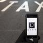 The logo of car-sharing service app Uber on a smartphone over a reserved lane for taxis in a street is seen in this photo illustration taken in Madrid on December 10, 2014. REUTERS/Sergio Perez