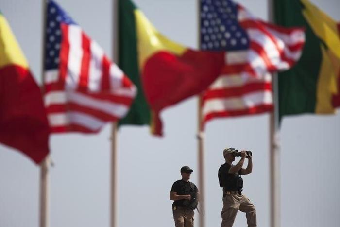 American security officers scan the airport from a rooftop below Senegalese and American flags before the departure of U.S. President Barack Obama in Dakar, Senegal, June 28, 2013. REUTERS/Joe Penney