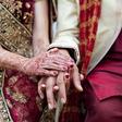 Bride and groom in traditional Indian wedding clothing with henna tattoos