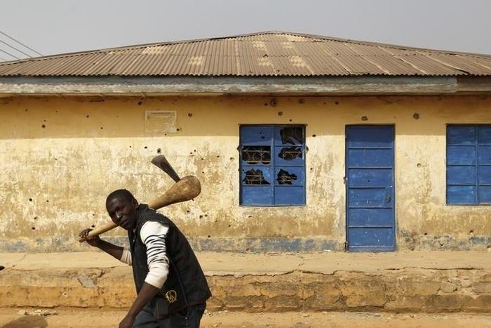 A man carrying an axe walks past a house marked with bullet holes in Gyallesu district after recent clashes between Shi'ites and the army in Zaria, Kaduna state, Nigeria, February 3, 2016. REUTERS/Afolabi Sotunde