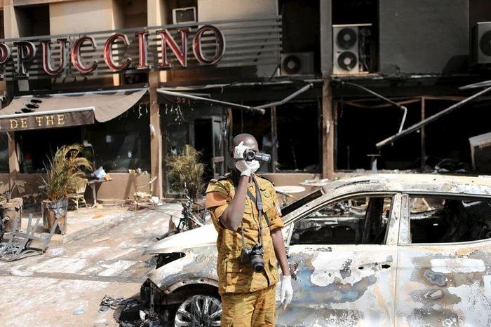 A Burkinabe soldier films in front of the burned-out exterior of "Cappuccino" restaurant in Ouagadougou, Burkina Faso, January 17, 2016. REUTERS/Joe Penney