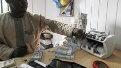 A bureau de change operator counts U.S. hundred dollar notes in Abuja, March 12, 2015. In Nigeria, holding naira has become increasingly unpopular as it has lost its value.  REUTERS/Afolabi Sotunde